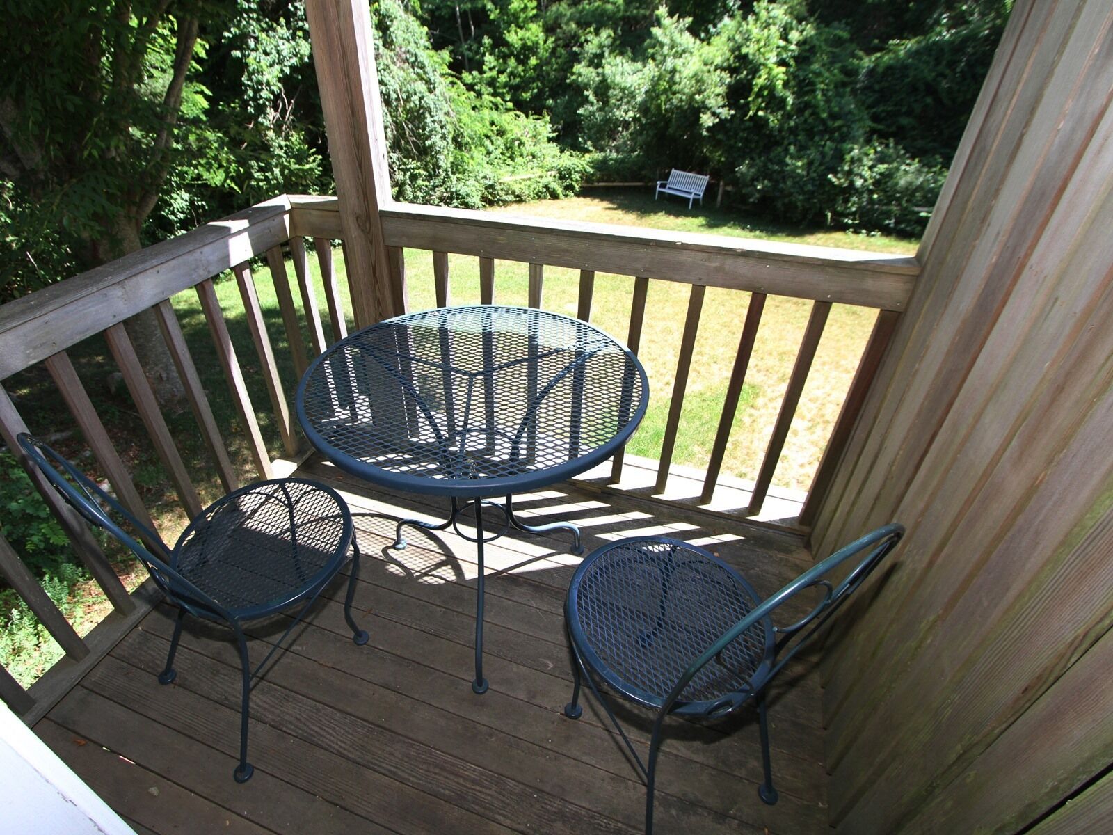 Une terrasse en bois avec une table ronde en métal et deux chaises.