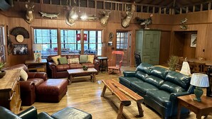 A rustic interior with leather sofas, wooden tables, and deer antlers on the walls. - Large SECLUDED RIVERFRONT Cabin with PRIVATE access to CANOE/KAYAK Blue River (Depauw)