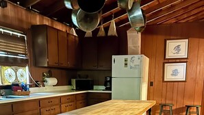 A kitchen with wooden cabinets, a wooden table, a refrigerator, and hanging pots. - Large SECLUDED RIVERFRONT Cabin with PRIVATE access to CANOE/KAYAK Blue River (Depauw)