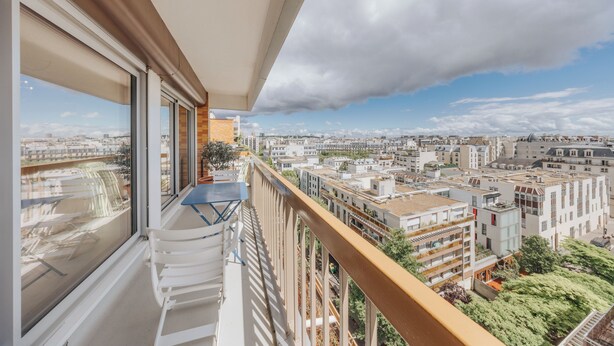 Un balcon offrant une vue sur le paysage urbain, avec ses bâtiments et sa végétation.