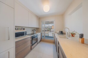 A modern kitchen with a microwave, oven, sink, and a view of a balcony.