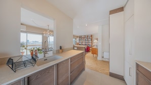 Une cuisine moderne dotée d’un grand îlot central, d’une bibliothèque intégrée et offrant une vue sur l’extérieur.