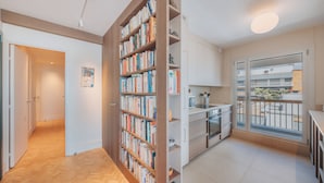 Un appartement moderne doté d’une bibliothèque en bois, d’une cuisine et d’un balcon avec vue.