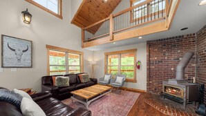 Una sala de estar con chimenea, muebles de cuero y ventanas amplias.