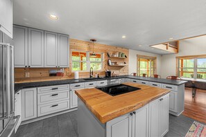 A modern kitchen with white cabinetry, a wooden island, and built-in shelves.