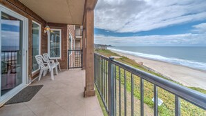 A balcony with a view of the beach, a wooden exterior, and a glass door entrance. - Condo #29 has AMAZING unsurpassed views of the Pacific Ocean! (Lincoln City)
