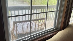 A window with a view of a wooden deck and outdoor furniture. - Waterfront 2 Bd cabin on Blue River, PRIVATE RIVER ACCESS, kayaking, fishing (Corydon)