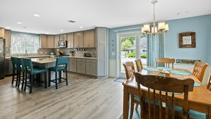 A modern kitchen with a central island, wooden chairs, and a dining table.
