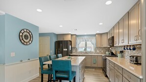 A modern kitchen with a central island, light blue walls, and wooden cabinetry.