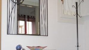A room with a wooden table, a mirror with a black frame, a coat rack, and a patterned floor. - TRAPANI HOLIDAY HOME LOW COST 2 (TRAPANI)