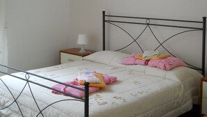 A single bed with a metal frame, a bedside table with a lamp, and a wall with two pieces of artwork. - TRAPANI HOLIDAY HOME LOW COST 2 (TRAPANI)
