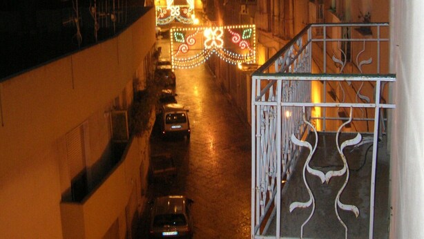 A narrow street with parked cars and a building with a metal gate. - TRAPANI HOLIDAY HOME LOW COST 2 (TRAPANI)