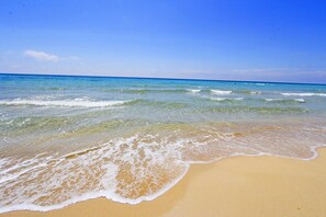 A beach with clear blue water and a sandy shore.