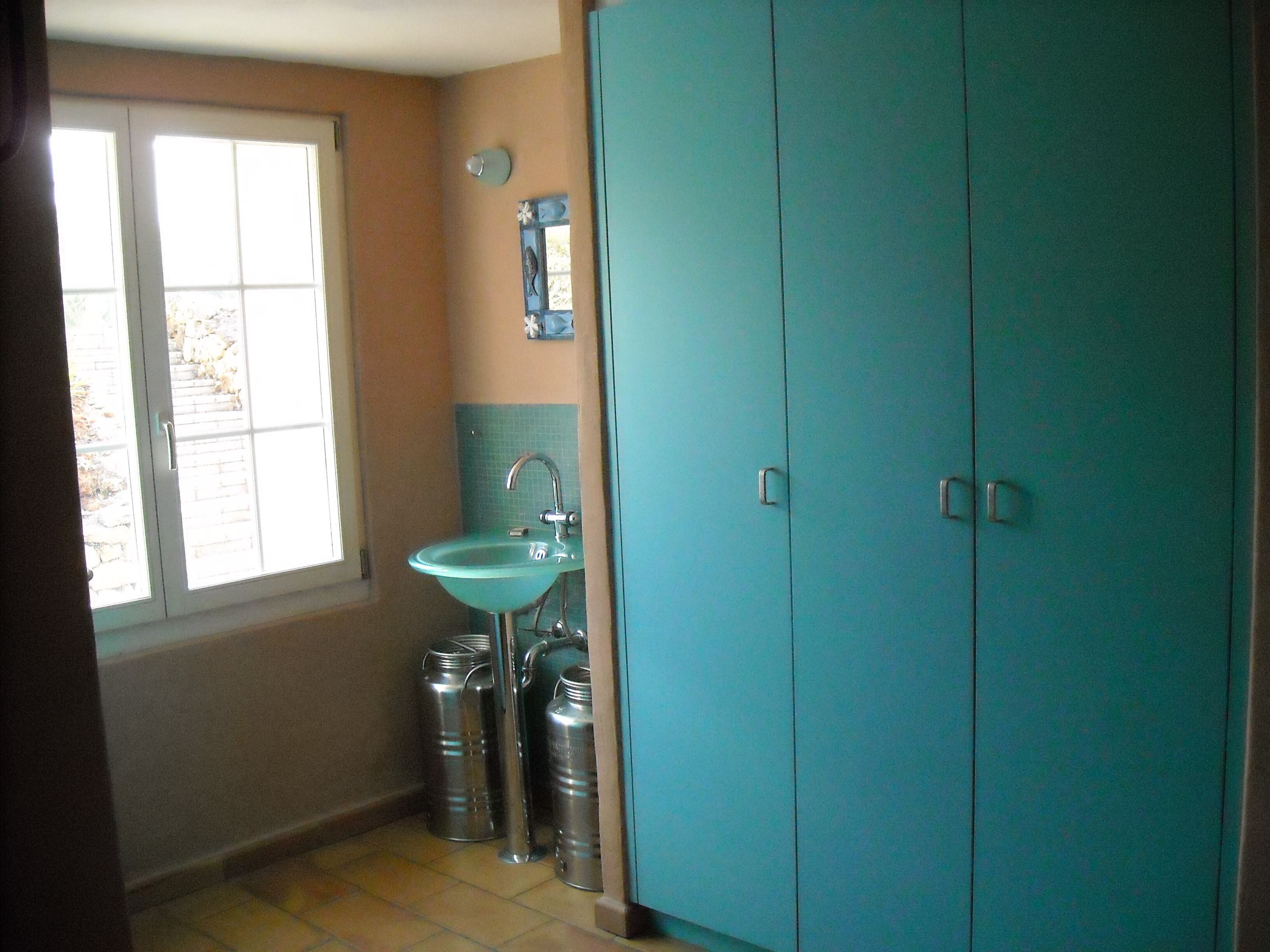 Ein Badezimmer mit Fenster, Waschbecken und Kleiderschrank.