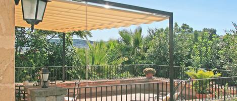 A patio area with a stone wall, metal railing, and a canopy providing shade.