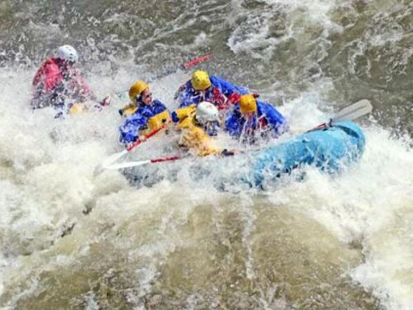 Un grupo de personas en un kayak blanco remando por un río caudaloso.