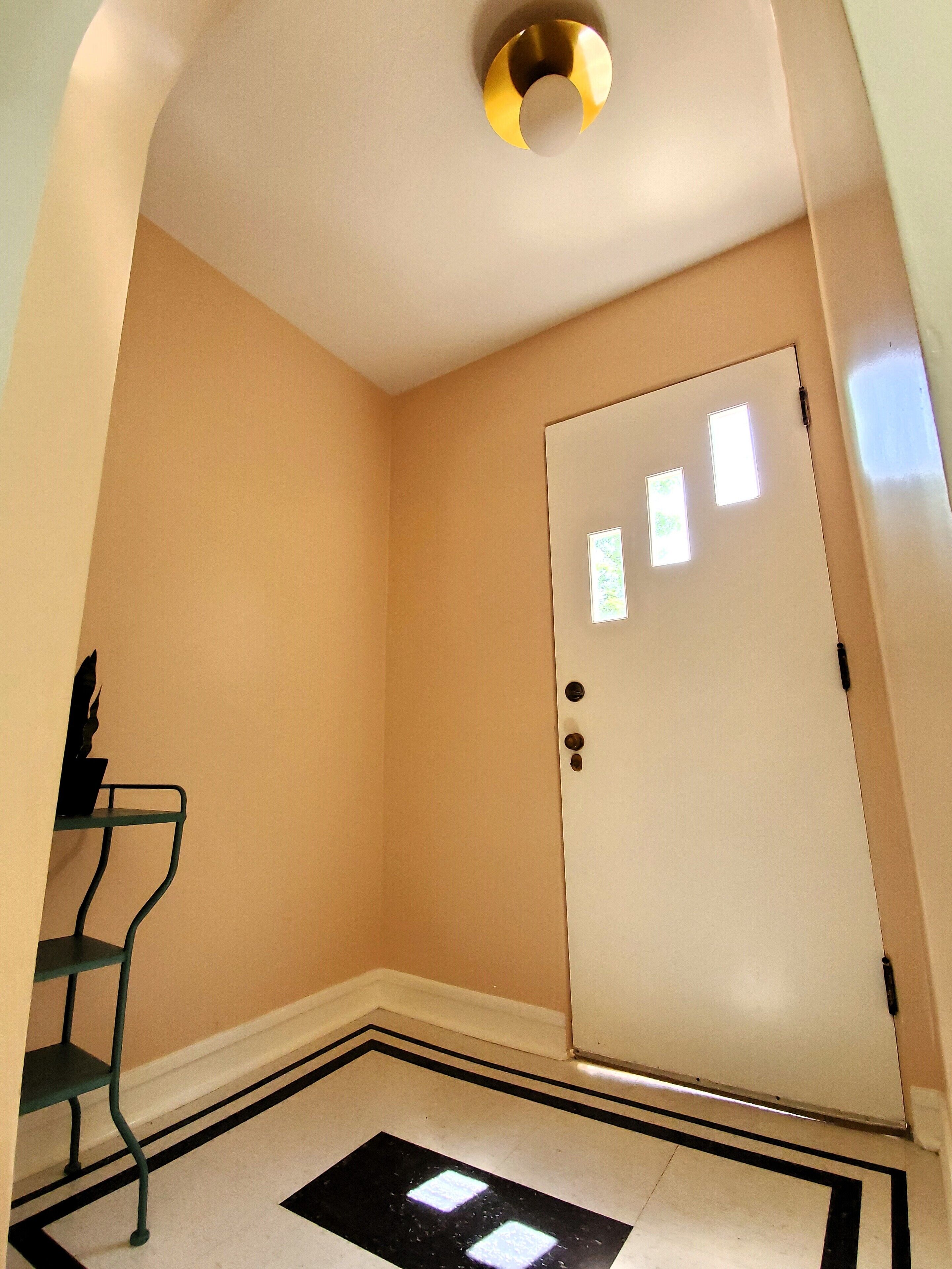 A room with a white door, a small window, and a black and white patterned floor.