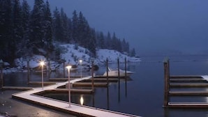 A waterfront dock with wooden platforms and a snow-covered landscape.