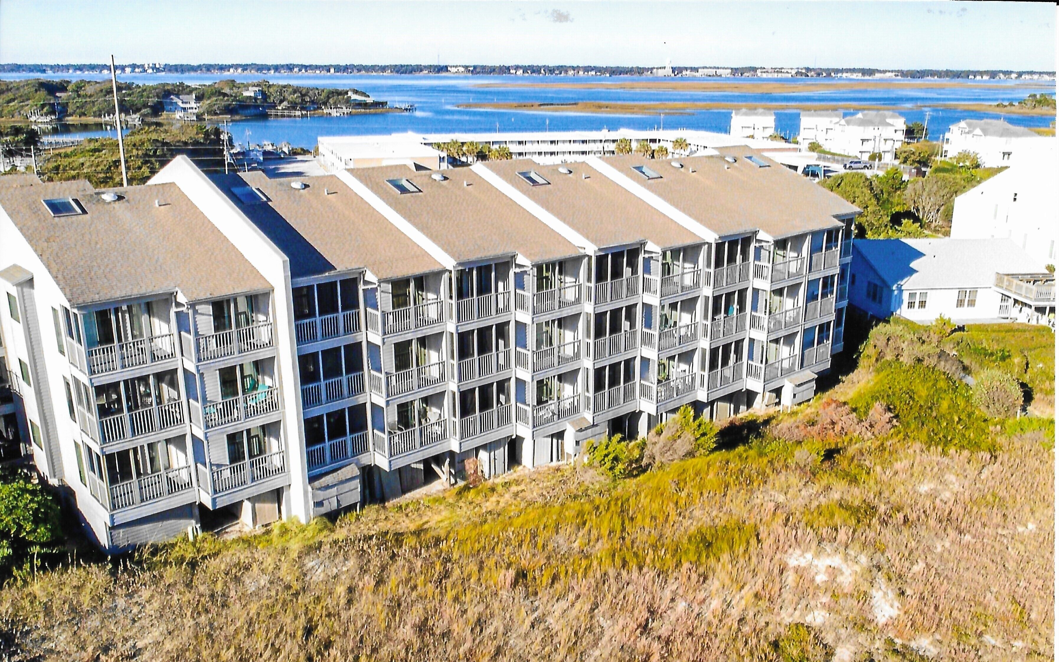 A multi-story hotel with balconies, located near a body of water.