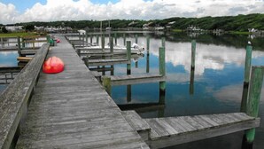 A wooden pier extending into calm water with docks and a boat.