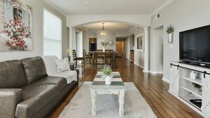A spacious living room with a leather couch, a coffee table, and a TV on a white cabinet. - GORGEOUS BEACH VIEW Legacy Towers T1-Unit 308/3 pools/Hot Tub/Close to Casinos (Gulfport)