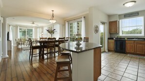 A spacious kitchen with a large island, wooden cabinets, and a dining area with chairs and a table. - GORGEOUS BEACH VIEW Legacy Towers T1-Unit 308/3 pools/Hot Tub/Close to Casinos (Gulfport)