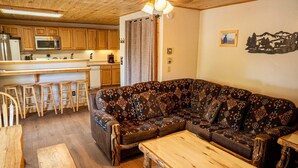Una sala acogedora con un sofá estampado, una mesa de centro de madera y taburetes de bar.