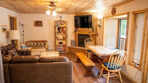Una sala de estar acogedora con un sofá, una mesa de madera, una chimenea y un televisor.