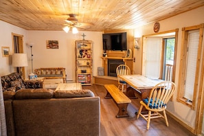 A cozy living room with a sofa, a wooden table, a fireplace, and a television.