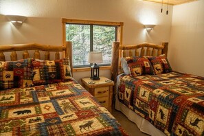 A bedroom with two beds, a window with blinds, a nightstand with a lamp, and a wooden headboard. - Nellie Gray #23 - Newly Remodeled with Amazing Views of Lake San Cristobal (Lake City)