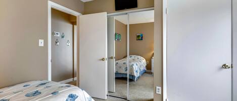 Une chambre à coucher comprenant un lit, une armoire, un miroir et un thermostat fixé au mur.