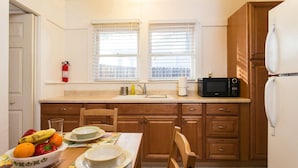 A compact kitchen with wooden cabinets, a microwave, a sink, and a fire extinguisher. - Classic & Central Hollywood Retreat with Porch and Garden (Los Angeles)