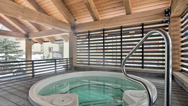 Ein Whirlpool unter einer Holz-Pergola mit Metallgeländern.