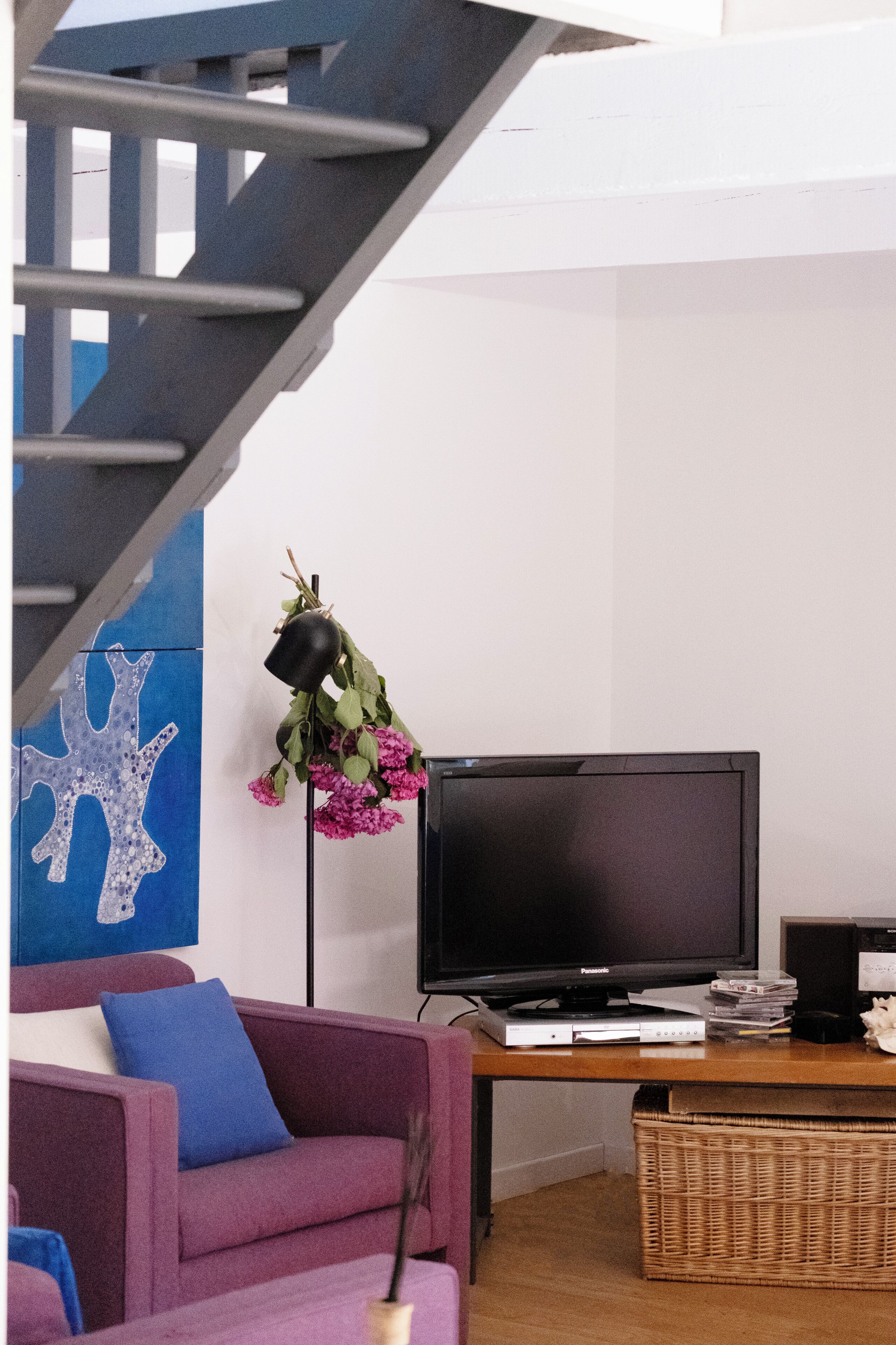 Un salon comprenant un escalier, un téléviseur à écran plat, un canapé, une table basse et un élément décoratif mural.