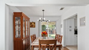 A dining room with a wooden table, chairs, and a cabinet with glass doors.