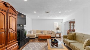 A living room with a wooden cabinet, a beige sofa, a coffee table, and a fireplace.
