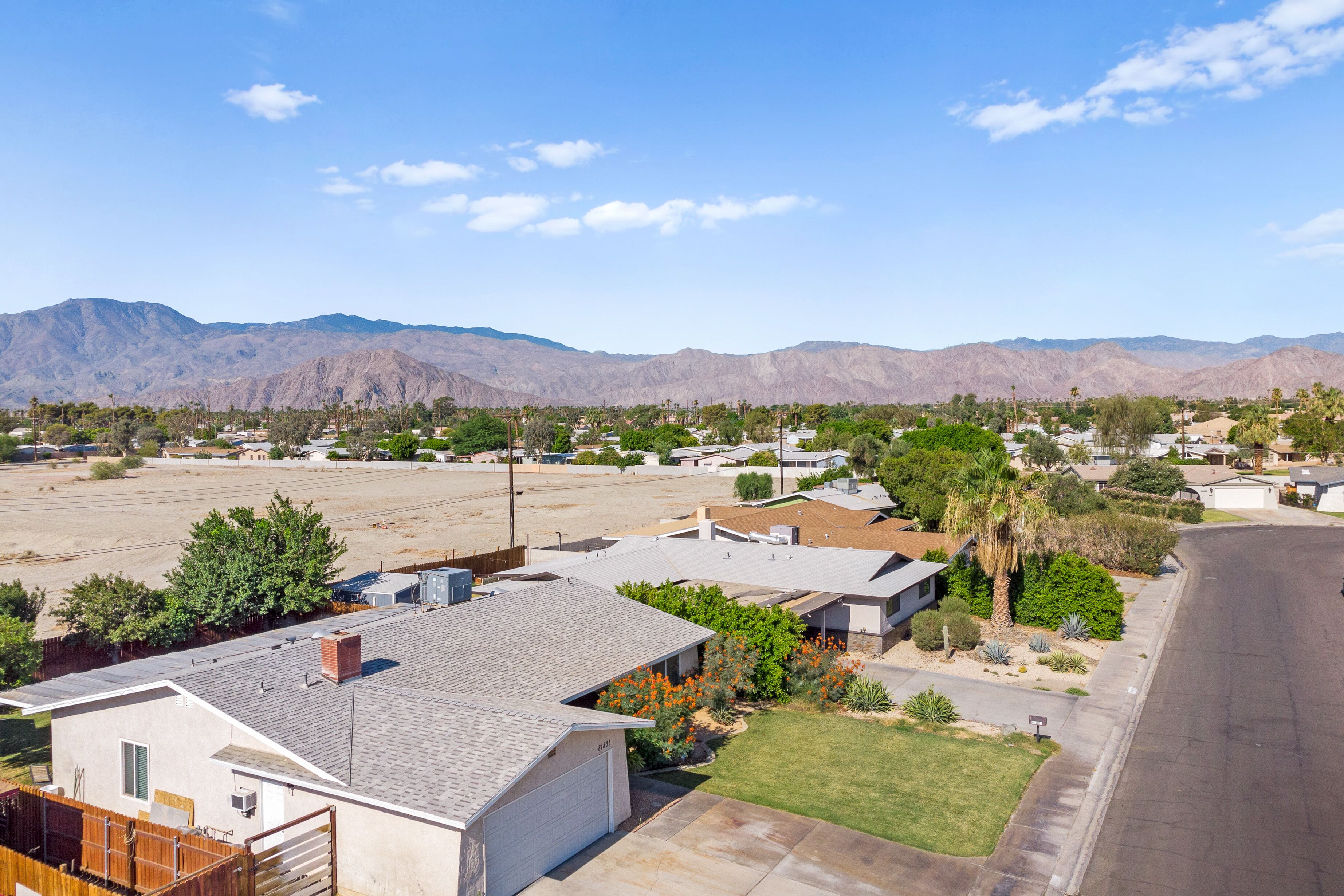 A residential area with houses, a street, and mountains in the background.