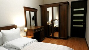 Une chambre d’hôtel avec un lit, une commode, un miroir et une armoire.