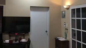A room with a ceiling fan, a flat-screen TV mounted on the wall, a dining table with chairs, a white door, and an air conditioning unit. - PRIVATE BEACH PATH a place to stay after you play all day! (Isabela)