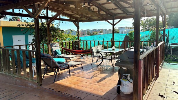 A covered outdoor patio with a wooden pergola, tiled flooring, and outdoor furniture including chairs and a table. - PRIVATE BEACH PATH a place to stay after you play all day! (Isabela)