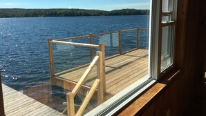 Une terrasse en bois avec une rambarde en verre donnant sur un lac.