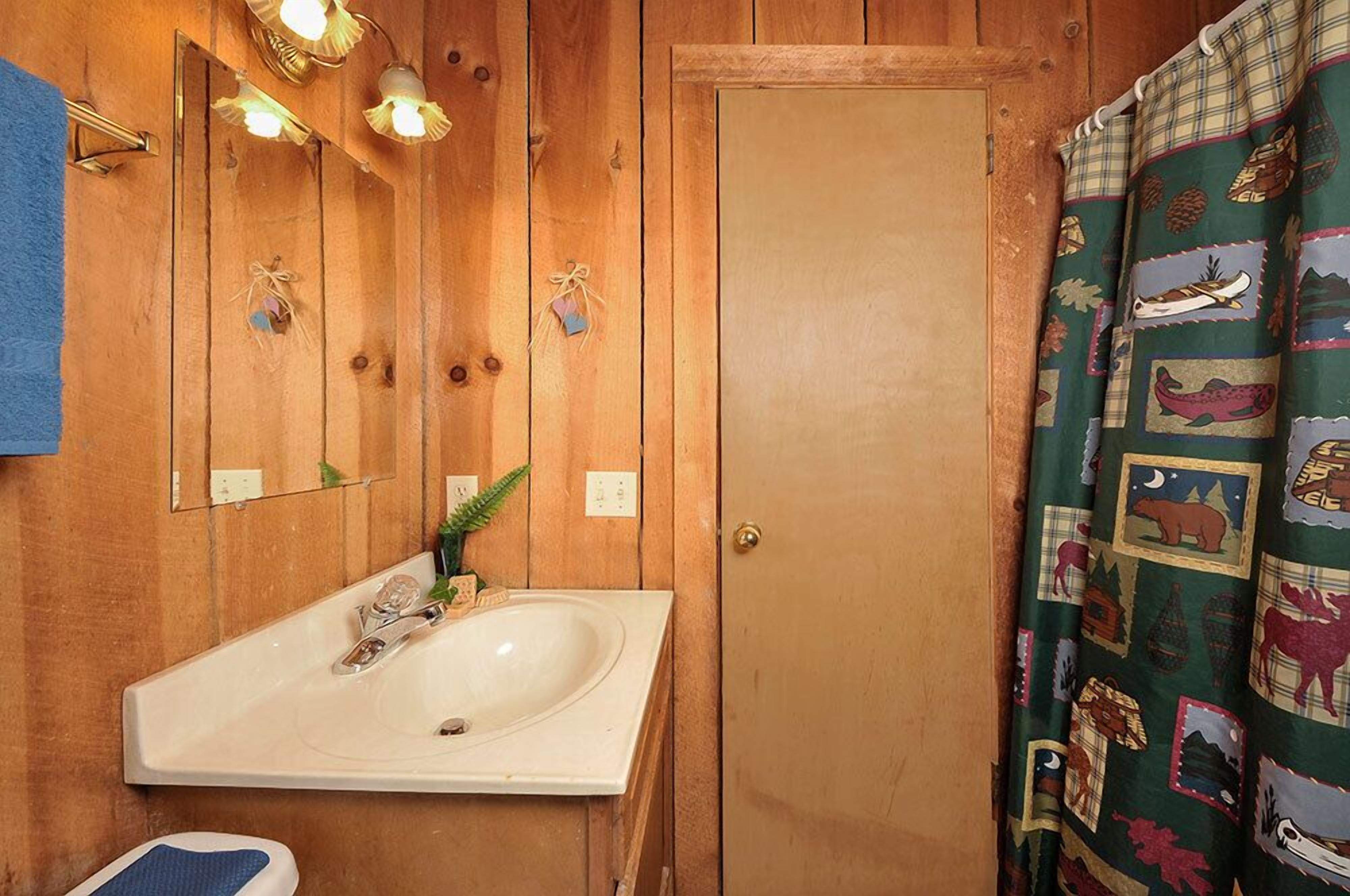 A wooden bathroom with a white sink, a mirror, and a door.