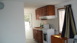 Een compacte keuken met houten kastjes, een magnetron, een kleine oven en een spoelbak.