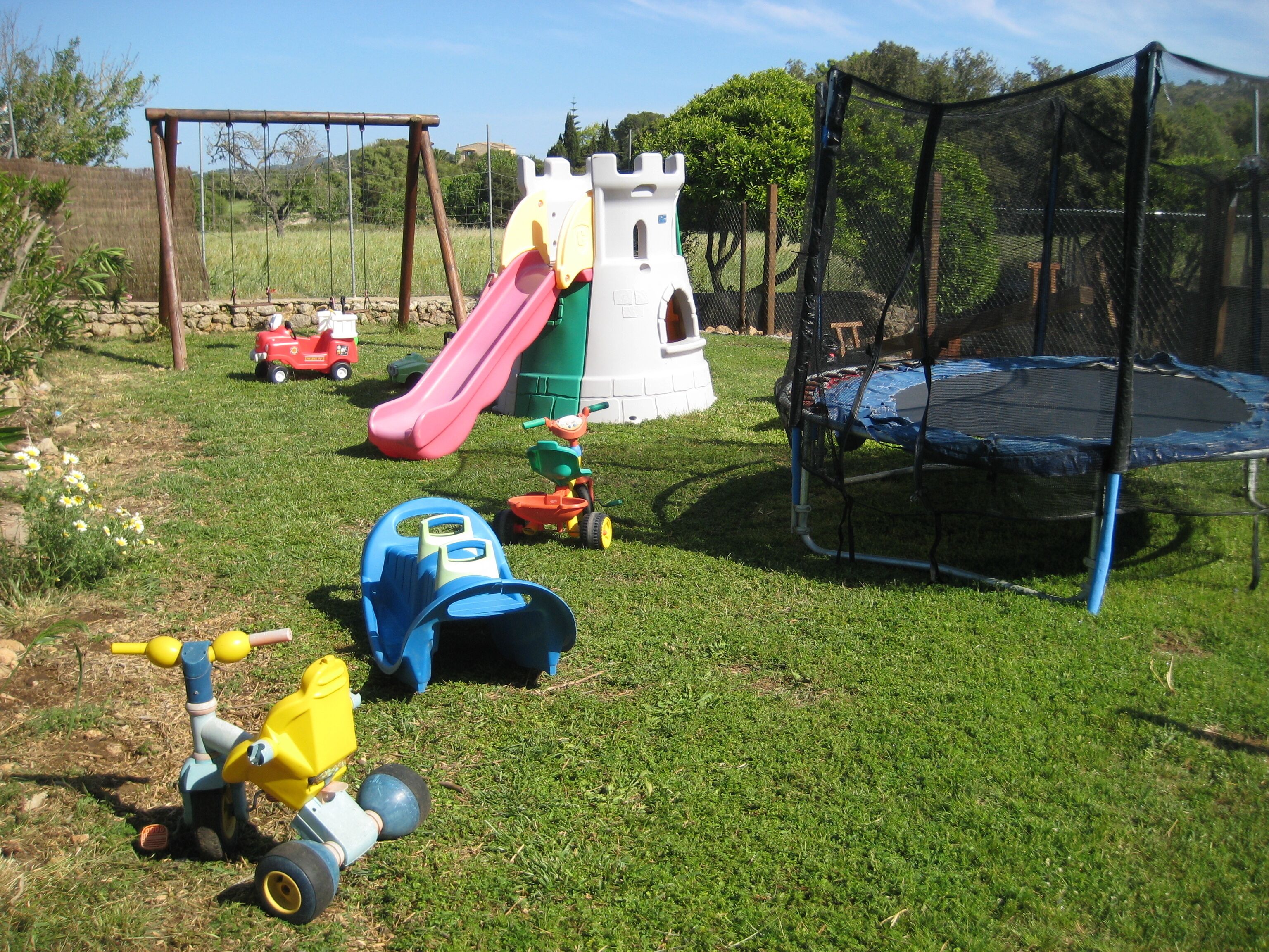 A playground with a slide, a swing set, and a trampoline.