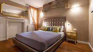 Un dormitorio con una cama grande, una mesita de noche de madera, un espejo y una pared de piedra decorativa.