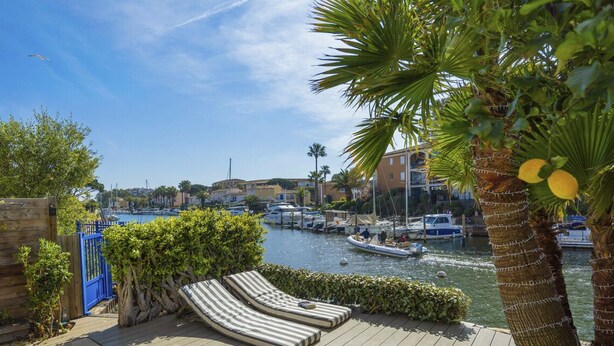 A marina with boats, a wooden deck, and a view of buildings in the background. - Superb Fisherman's House with Private Pool / Mooring - Port Grimaud (Grimaud)