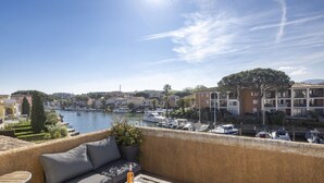 A balcony with a view of a marina, boats, and buildings in the background. - Superb Fisherman's House with Private Pool / Mooring - Port Grimaud (Grimaud)