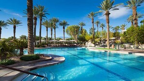 Une piscine entourée de palmiers et de chaises longues.