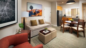 Una sala de estar moderna con sofá, reposapiés y comedor con sillas y mesa.