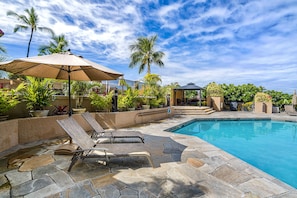 Relax by the serene pool surrounded by lush tropical plants and lounge under a shaded area.